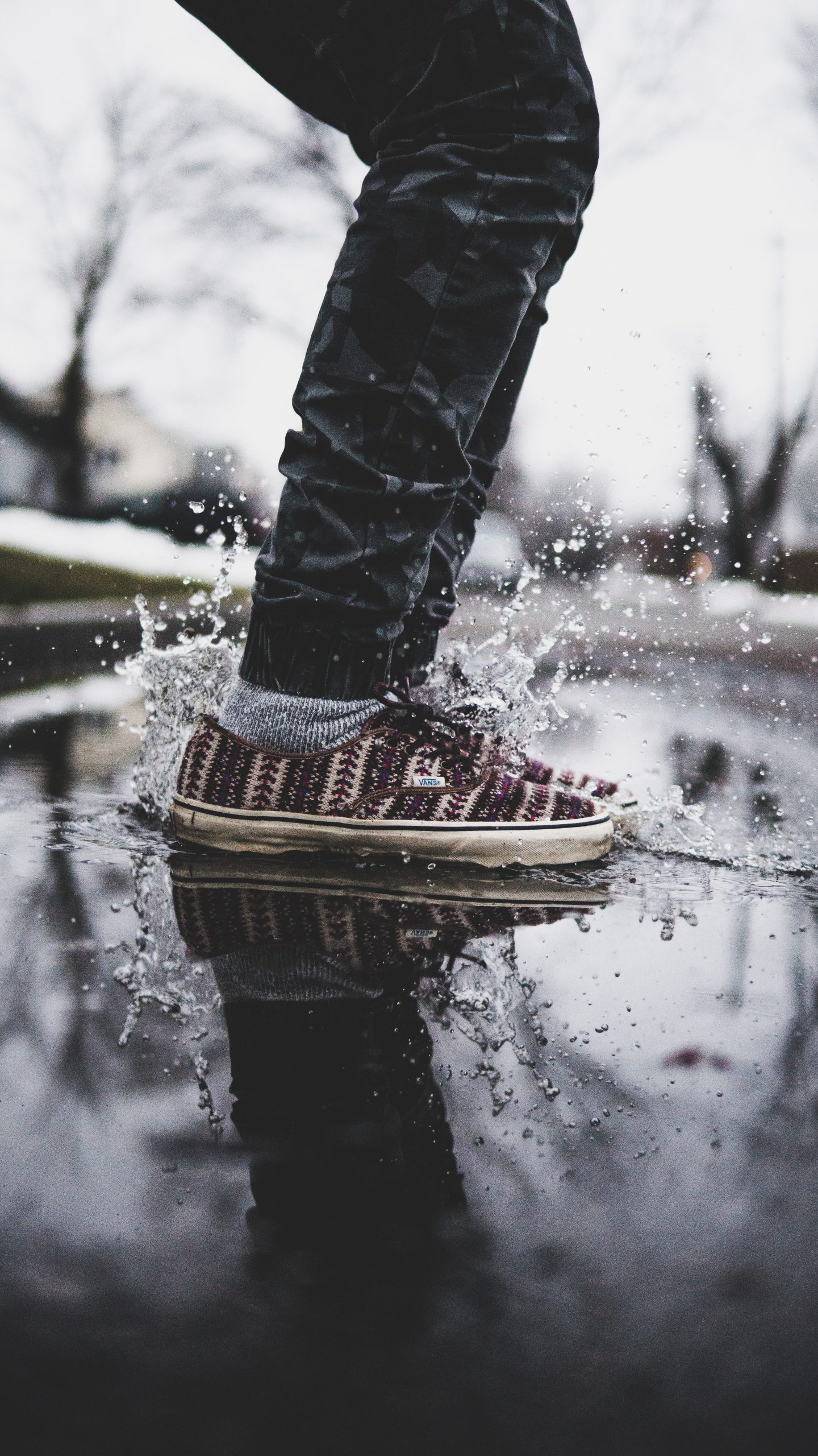 person wearing black pants and black-and-white low-top sneakers on wet floor